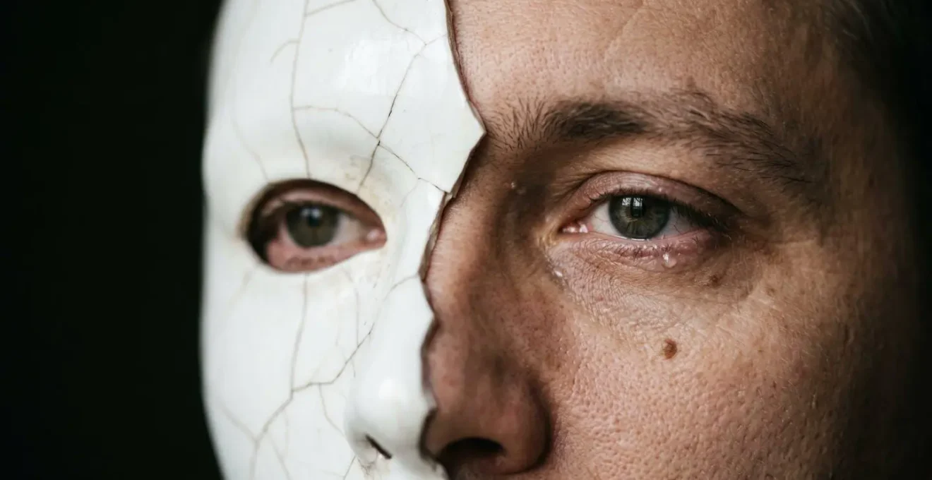Masque brisé révélant un visage authentique, symbolisant le danger de la fausse vulnérabilité